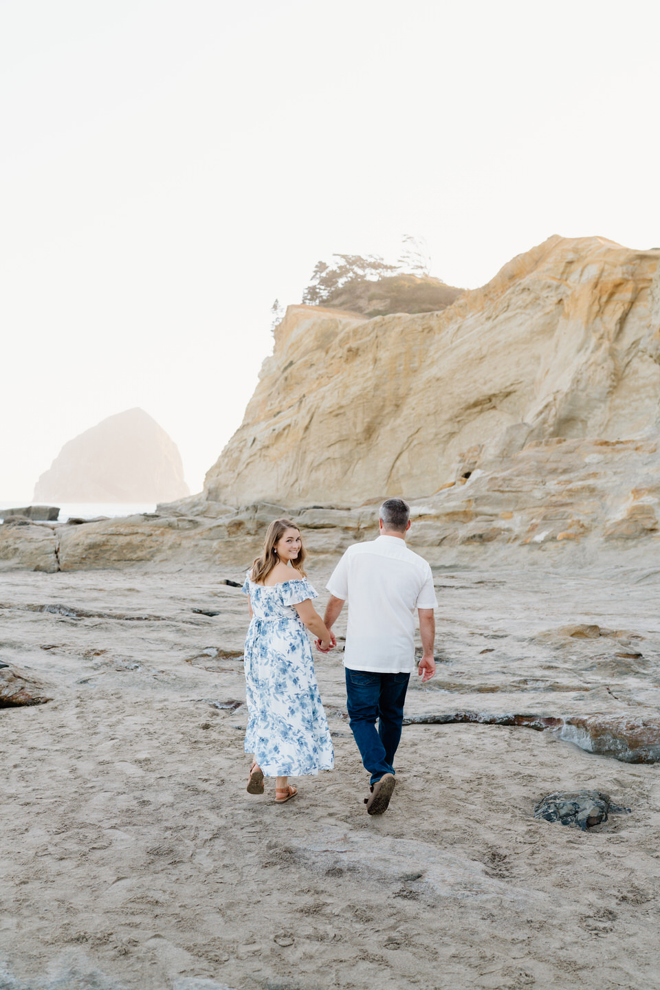 Couple walks along the rocky coastline at Cape Kiwanda