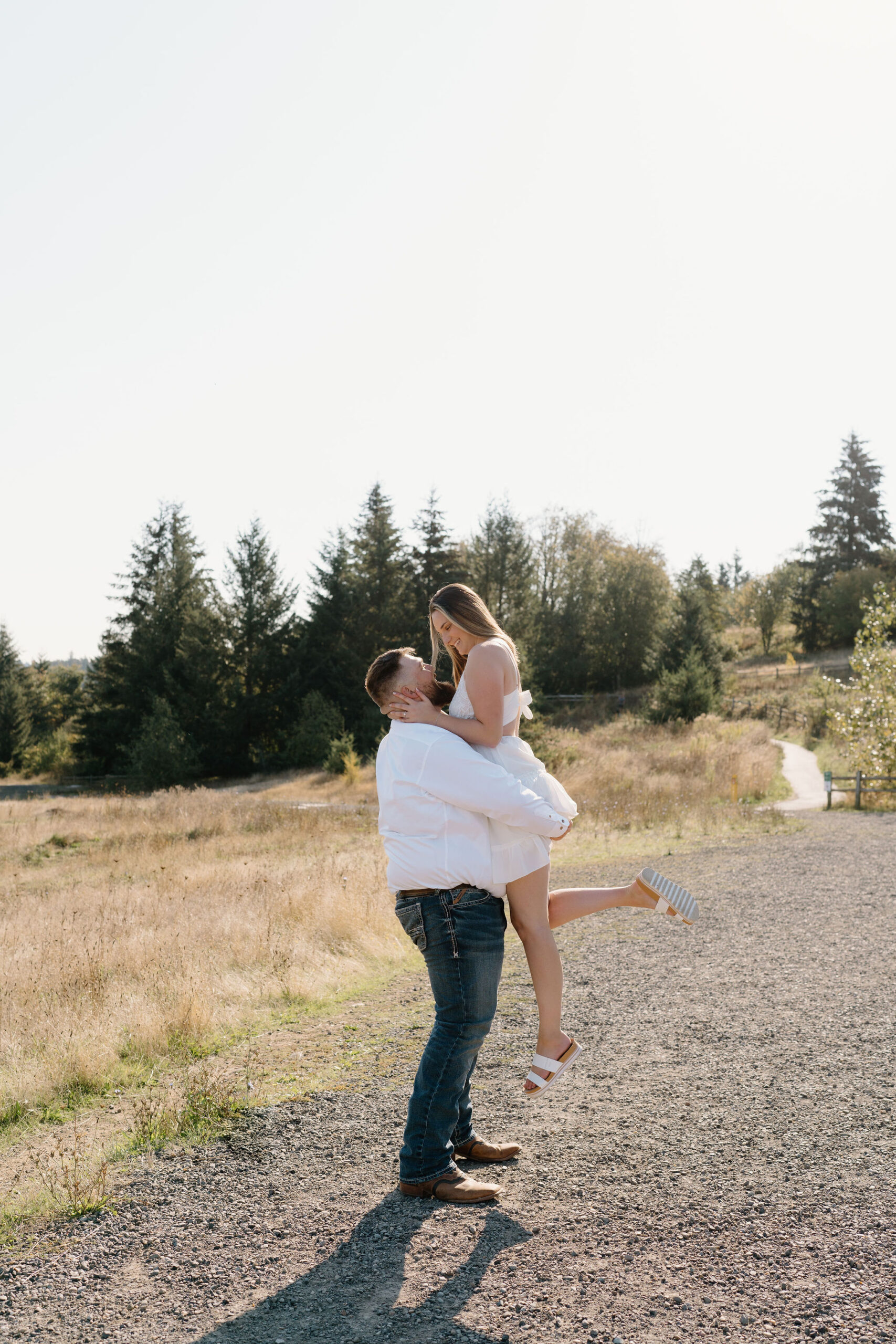Engaged couple takes engagement photos on the gravel path at Powell Butte Nature Park.