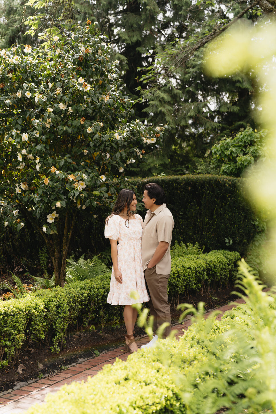Couple dressed in spring attire among the lush greenery of the Portland Rose Garden