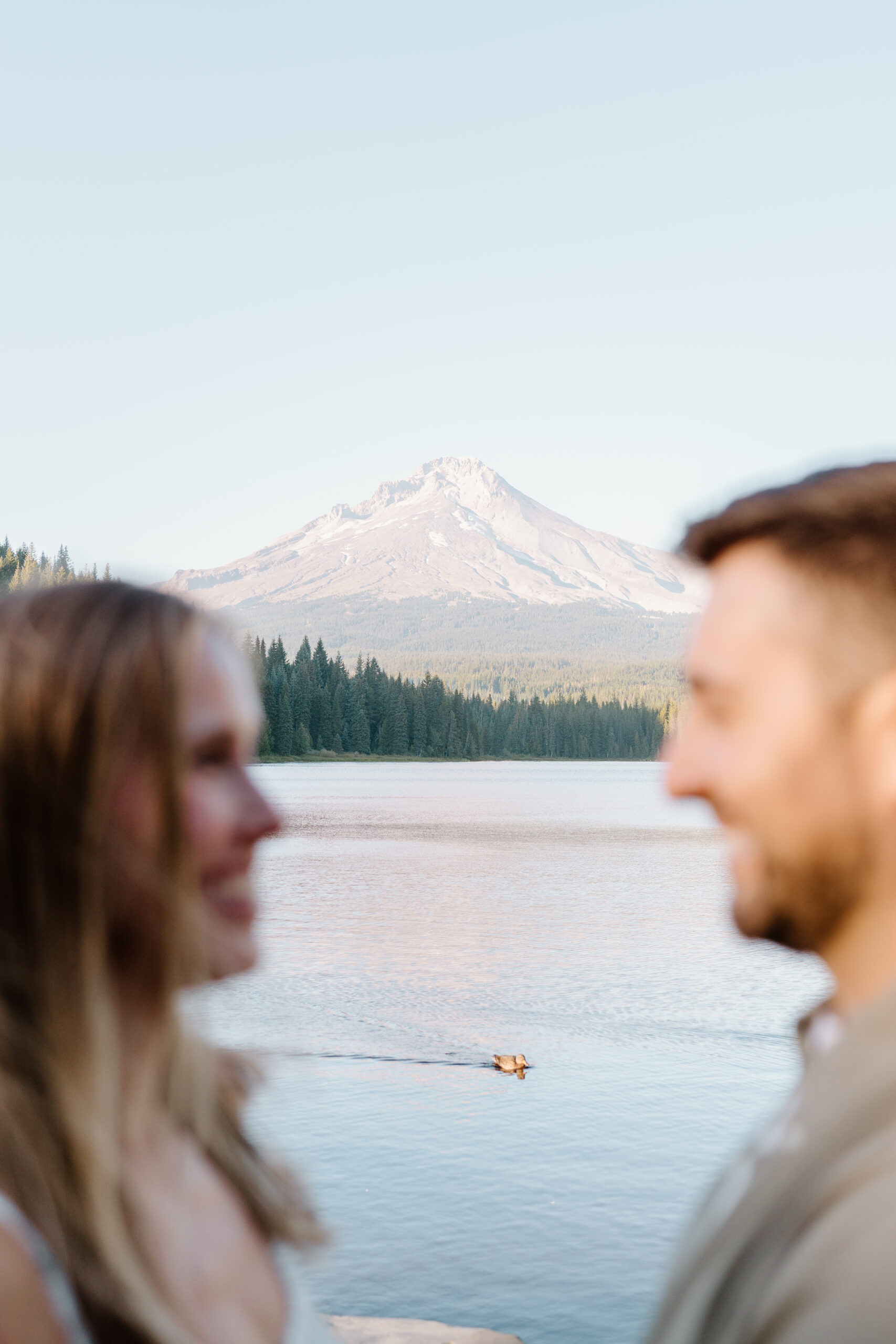 Silhouette of couple looking at each other with a scene of a duck on the water in front of Mt. Hood.
