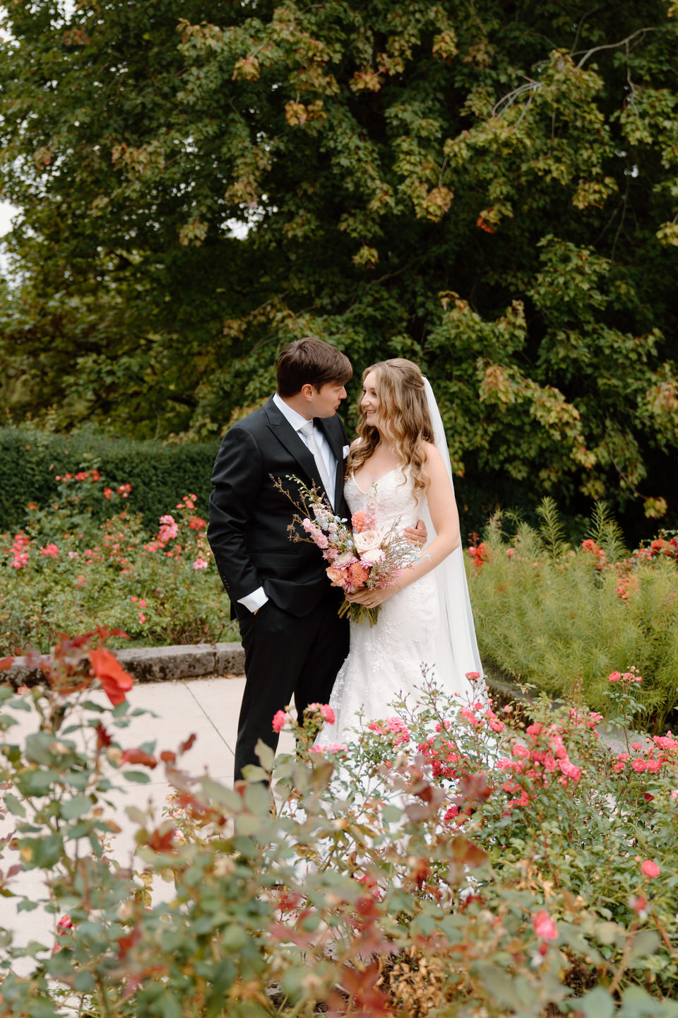 Bride and groom share a quiet moment for their wedding photos amongst the roses of Portland's International Rose Test Garden.