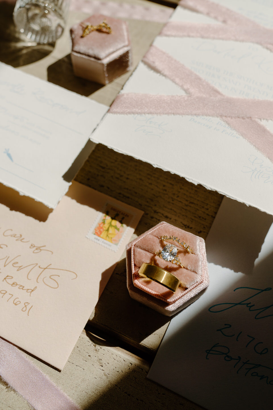Sunlight filters over the vellum invitation, creating soft shadows on the textured fabric and floral details.