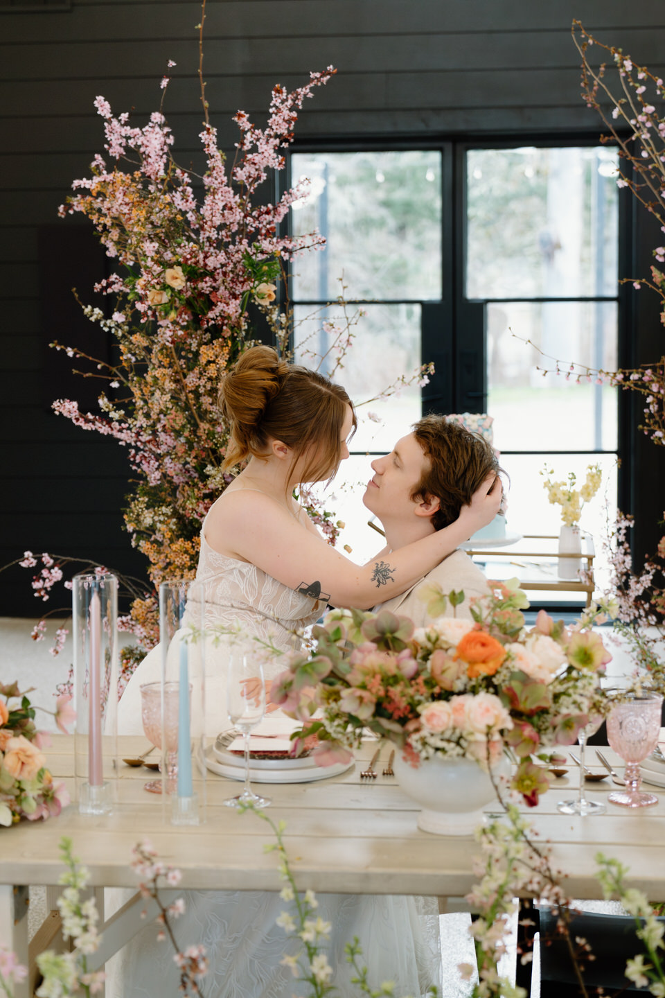 The sweetheart table at Sage & Social glows with pink florals, layered textures, and candlelight ambiance.