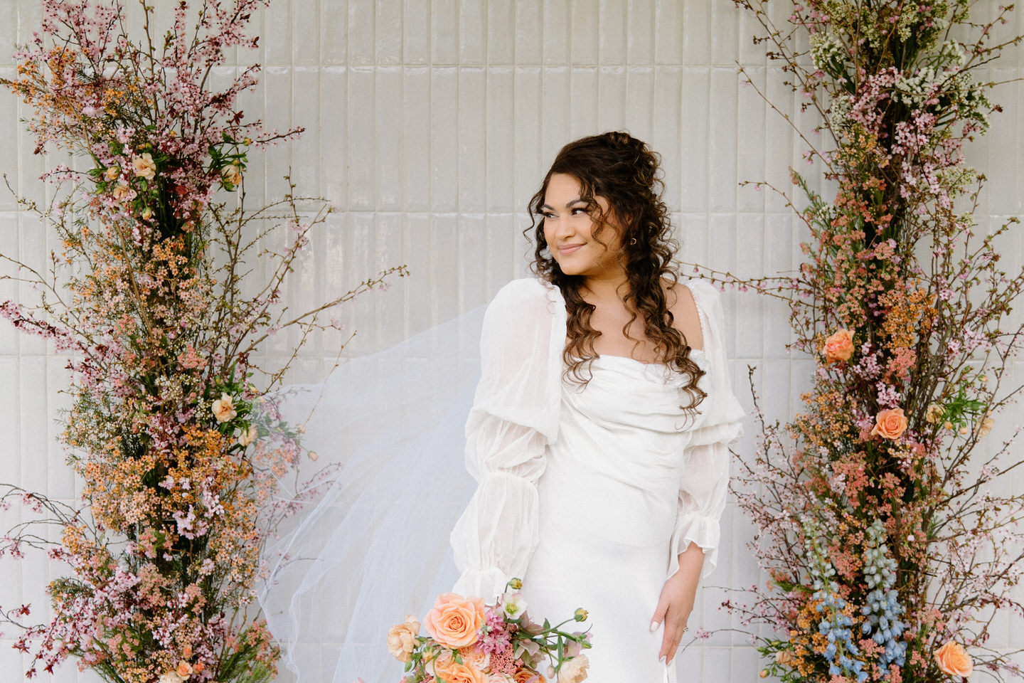 A dreamy bridal portrait in a flowing gown, framed by greenery and spring florals at Sage & Social.