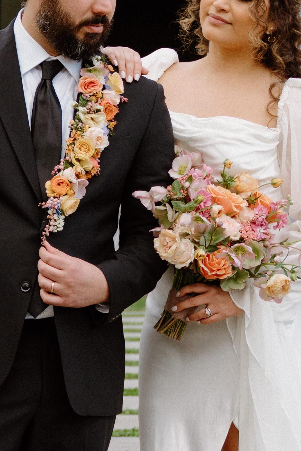 The bride holds her partner’s hand as they walk through the lush spring landscape, radiating joy and love.