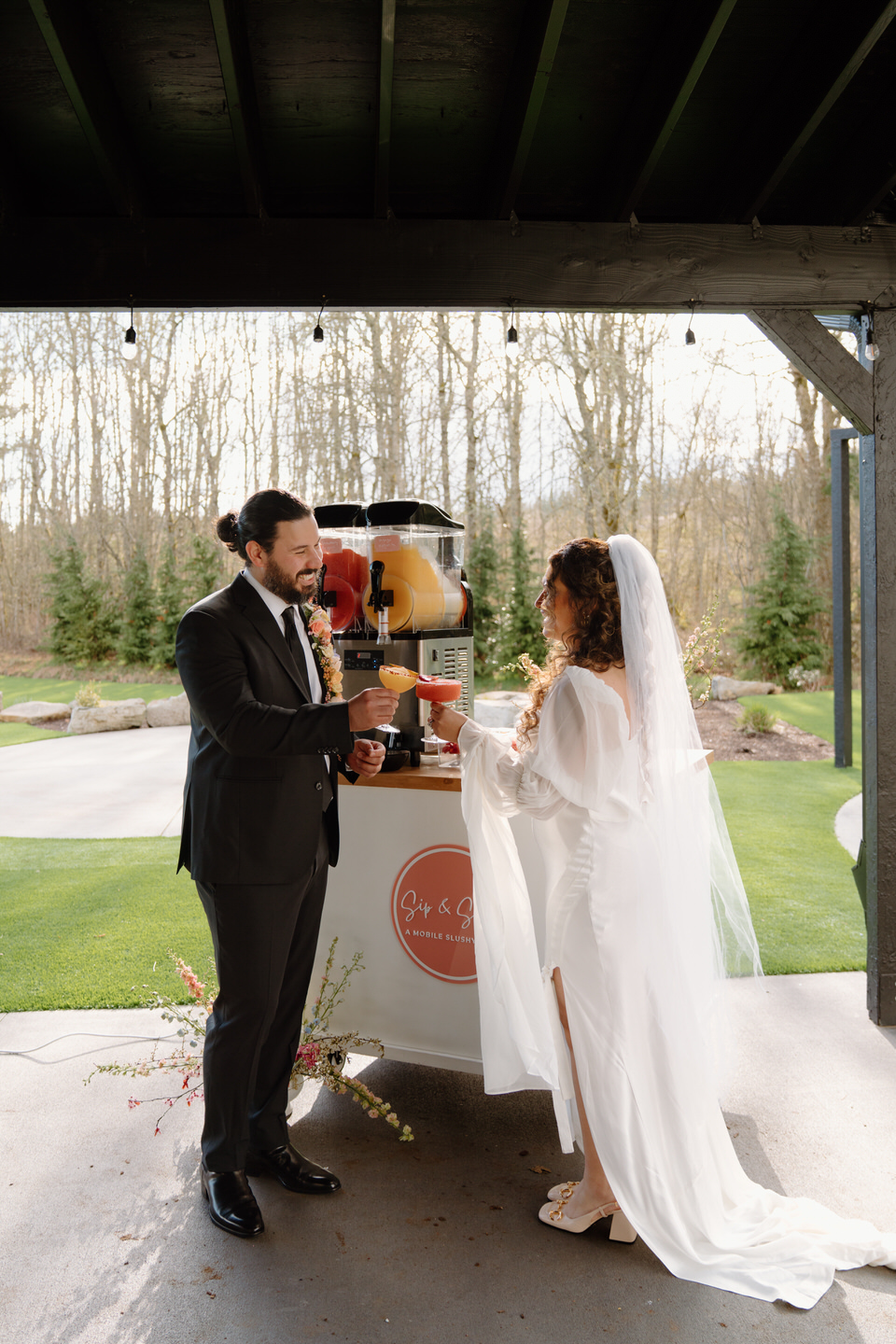 The bride’s train flows behind her as she and her partner stand together, bathed in the warm, golden sunlight at Sage & Social.