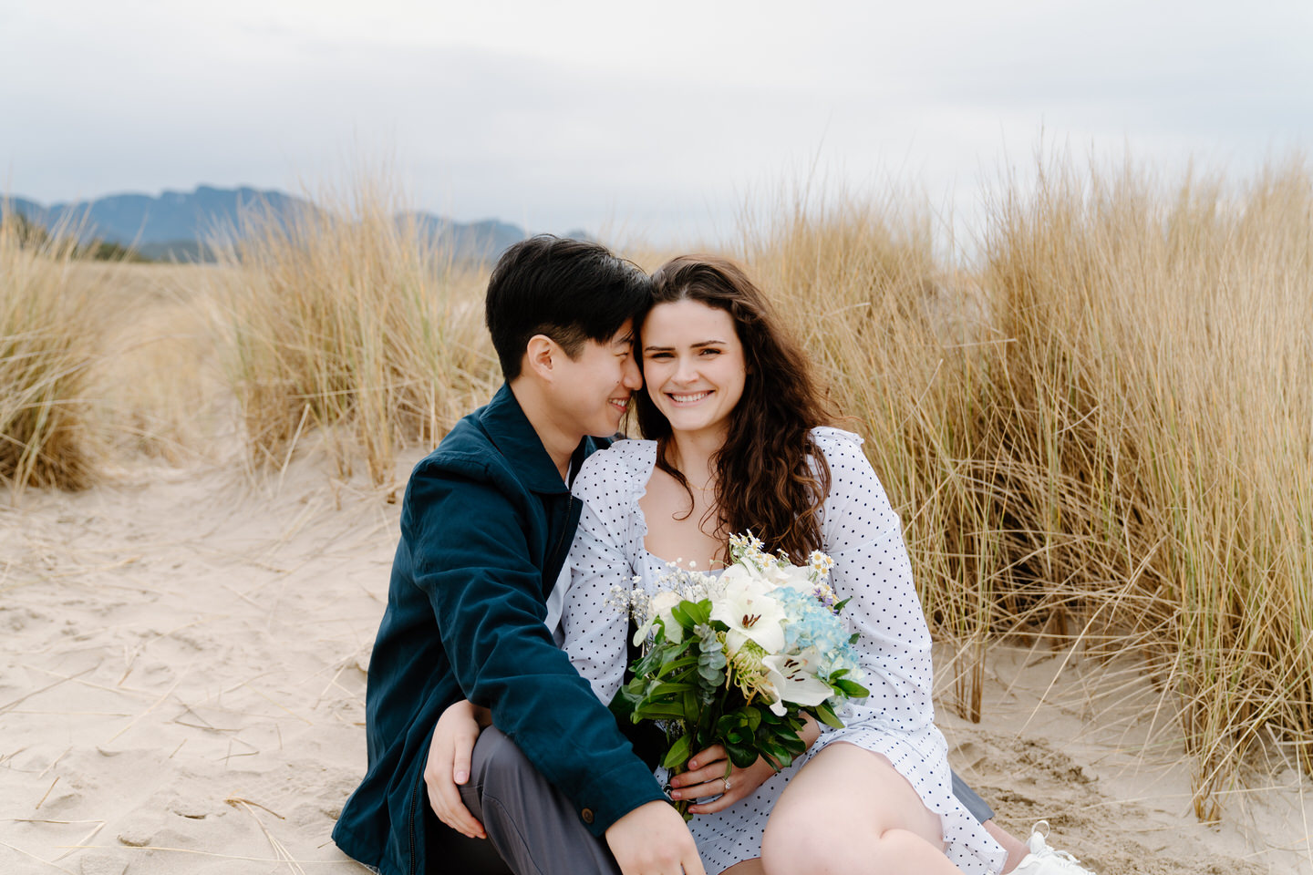 Backlit image of couple laughing with wild beach grasses behind them.