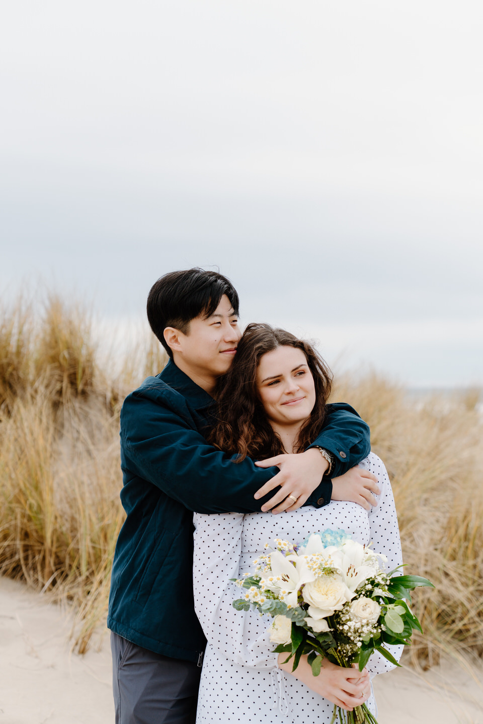 Couple embracing on Cannon Beach for Oregon coast engagement photos.