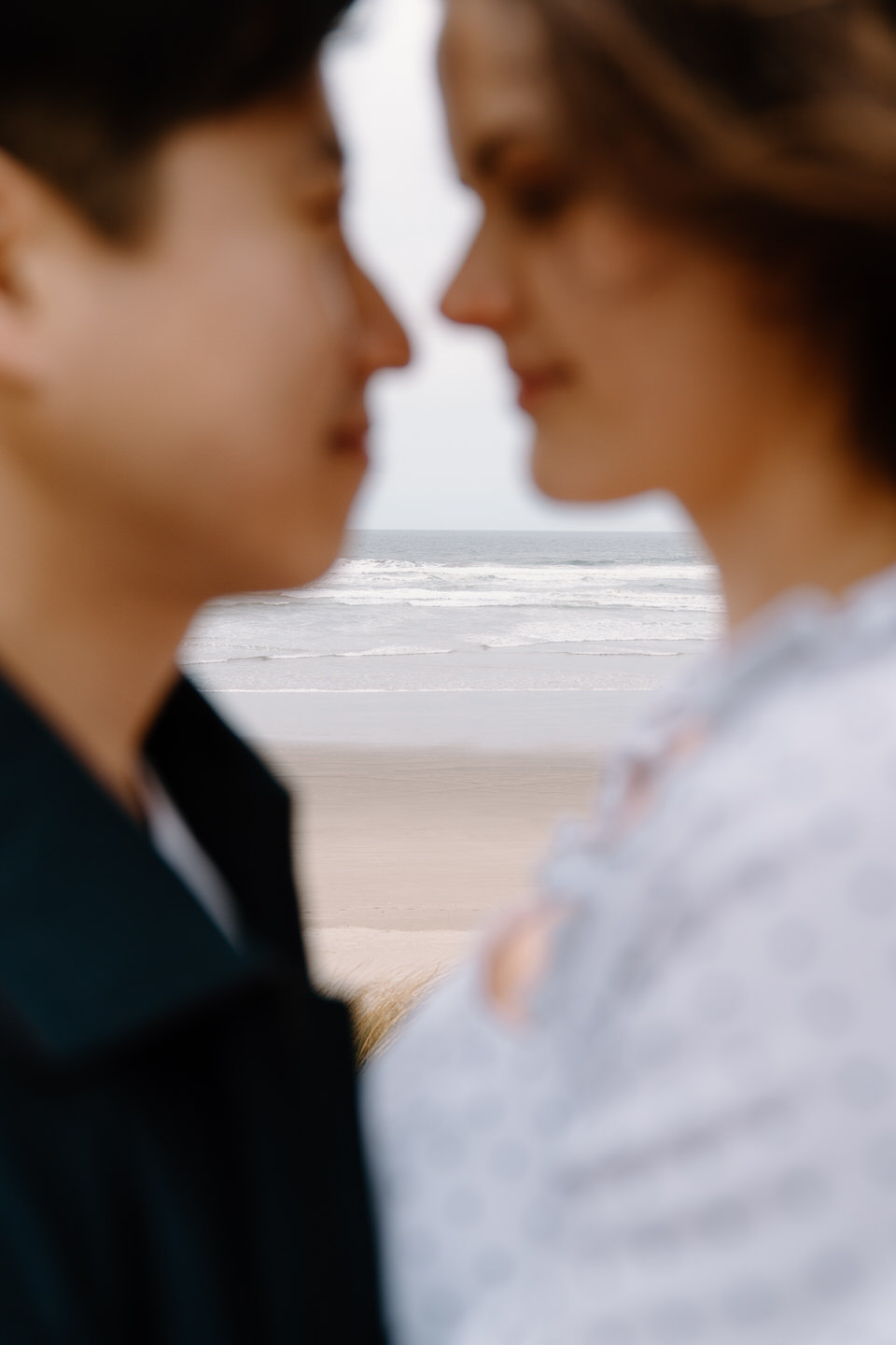 Soft focus of couple touching foreheads with moody sky in the background.