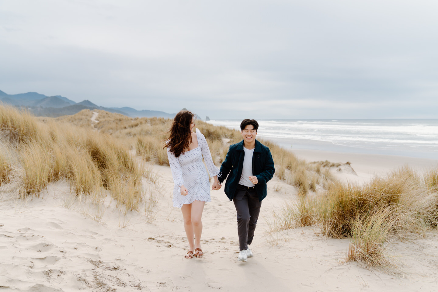 Joyful moment as couple smiles while walking through coastal dunes