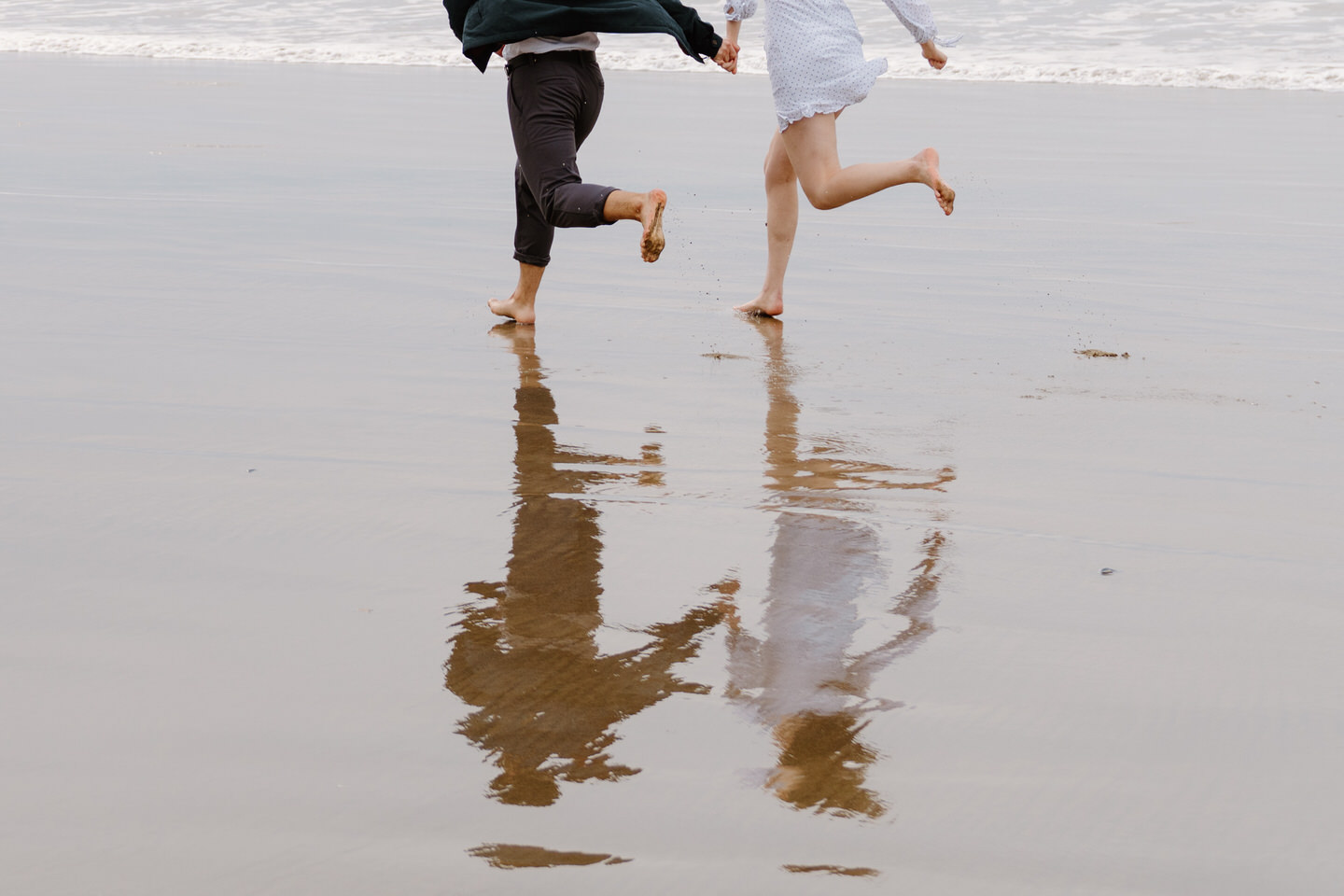 Joyful run along the shoreline during their Oregon coast engagement session.