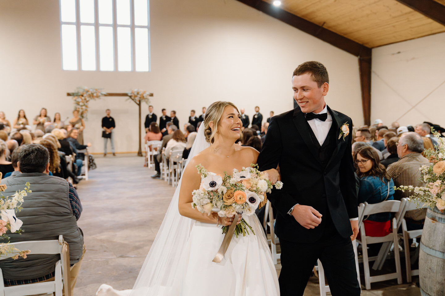 Bride and groom cheerfully walk down the aisle after getting married.