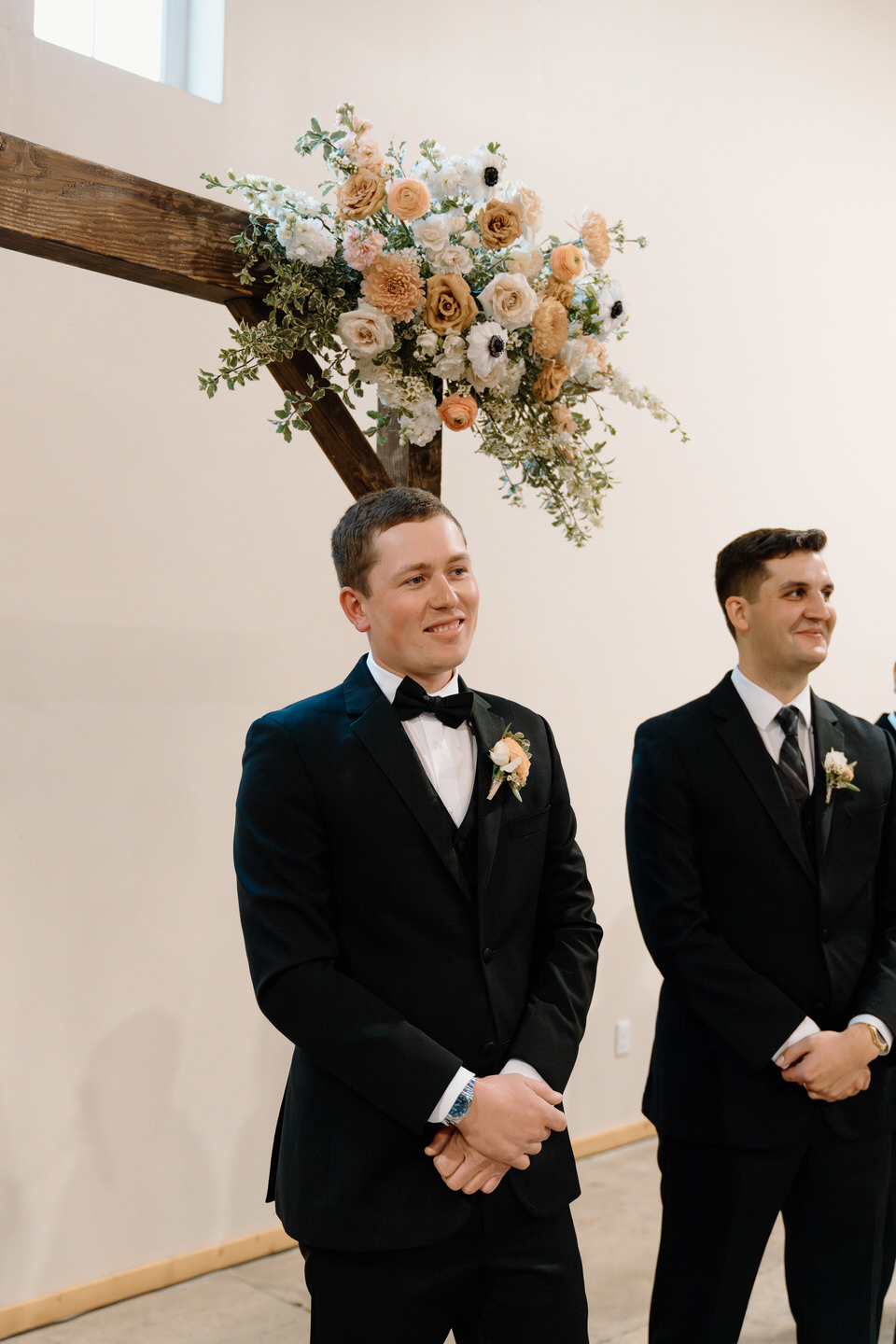 Groom smiles as his bride walks down the aisle towards him.