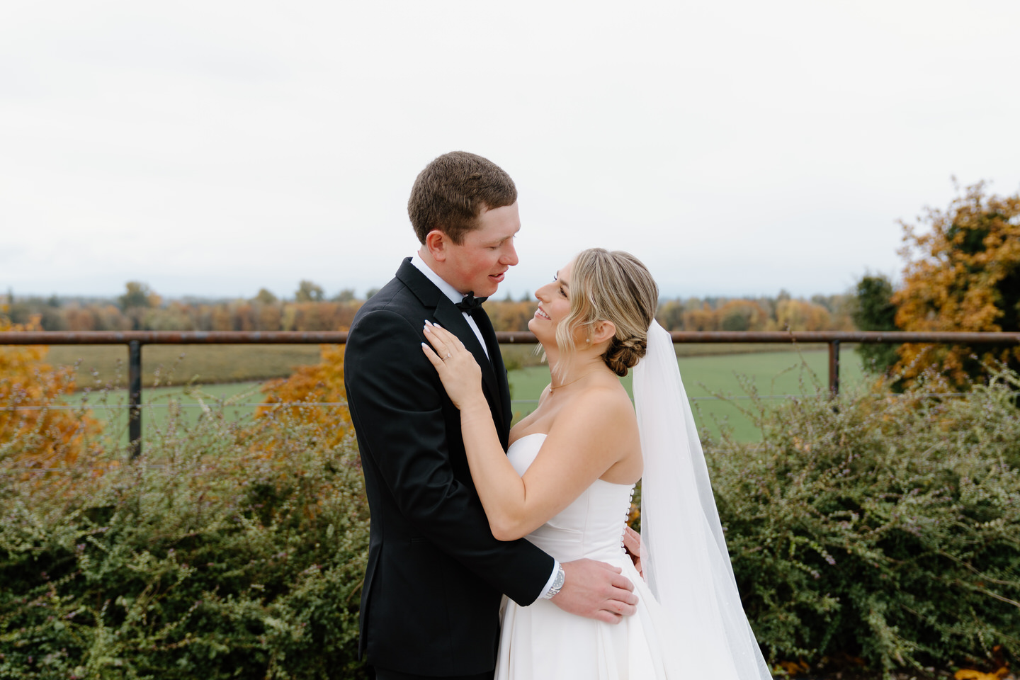 Bride and groom pose for portraits in front of Oregon's November foliage.