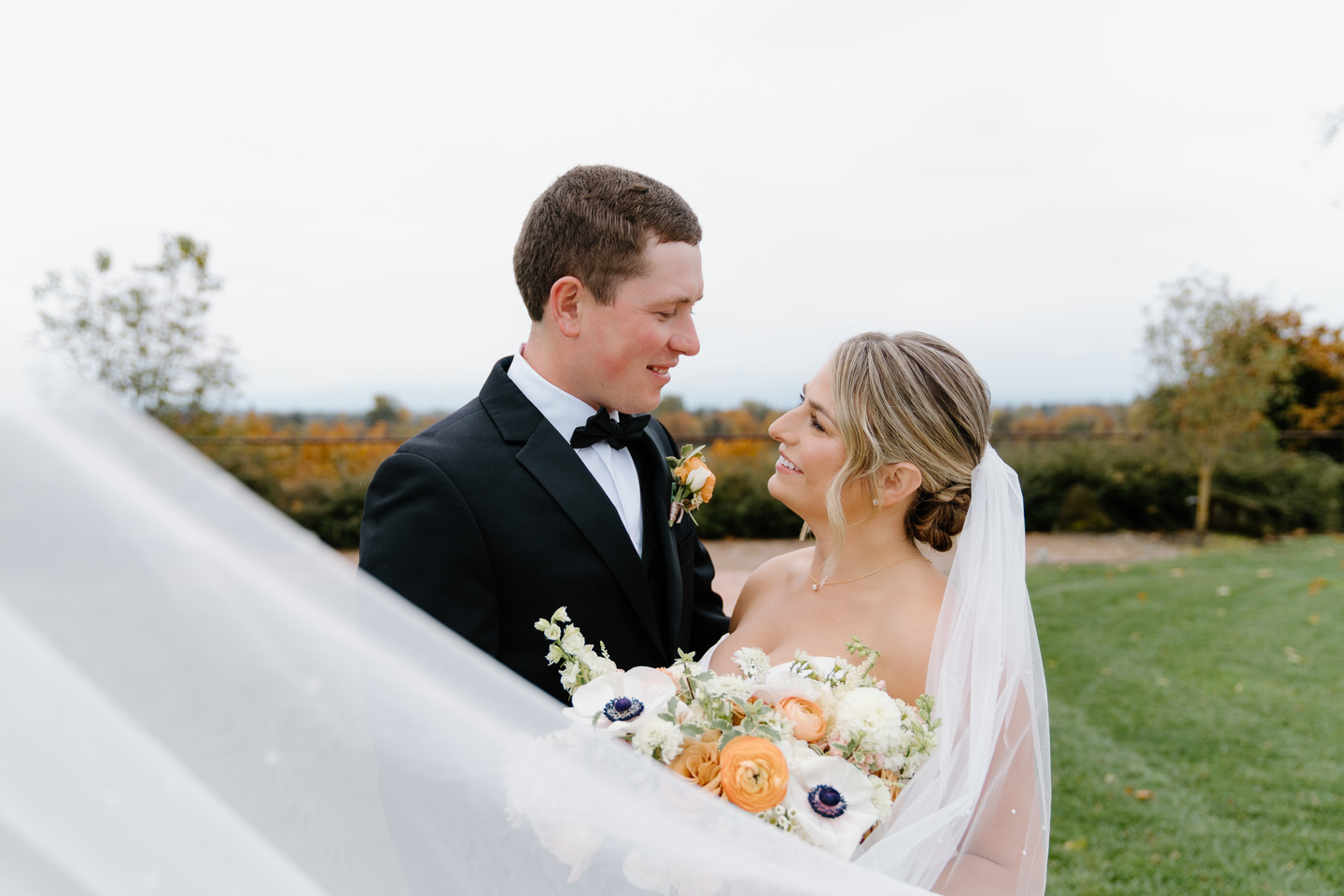 Bride and groom pose together with her veil swooped in front of them.