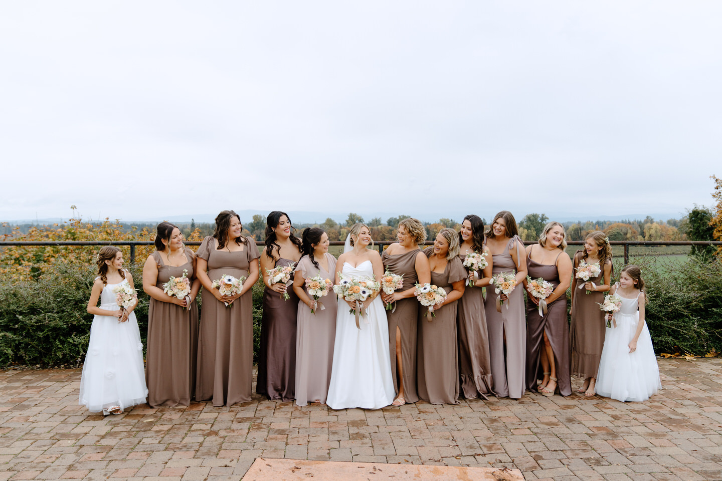 Bridesmaids smile at each other in their mocha brown dresses.