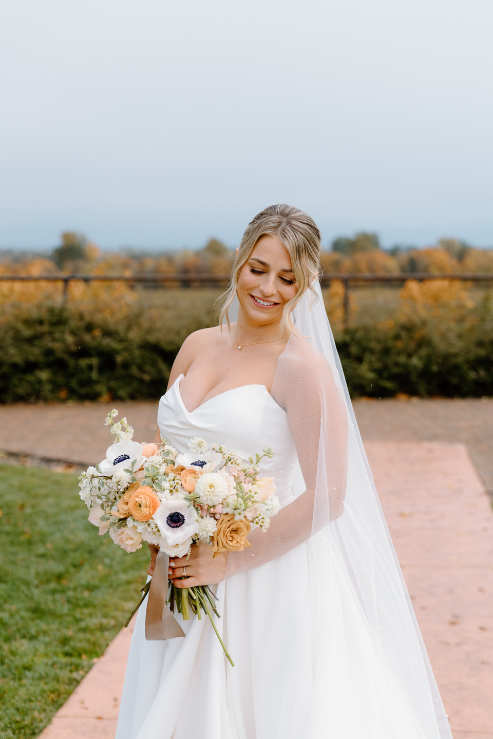 Solo bride portrait, gazing down past her bouquet.