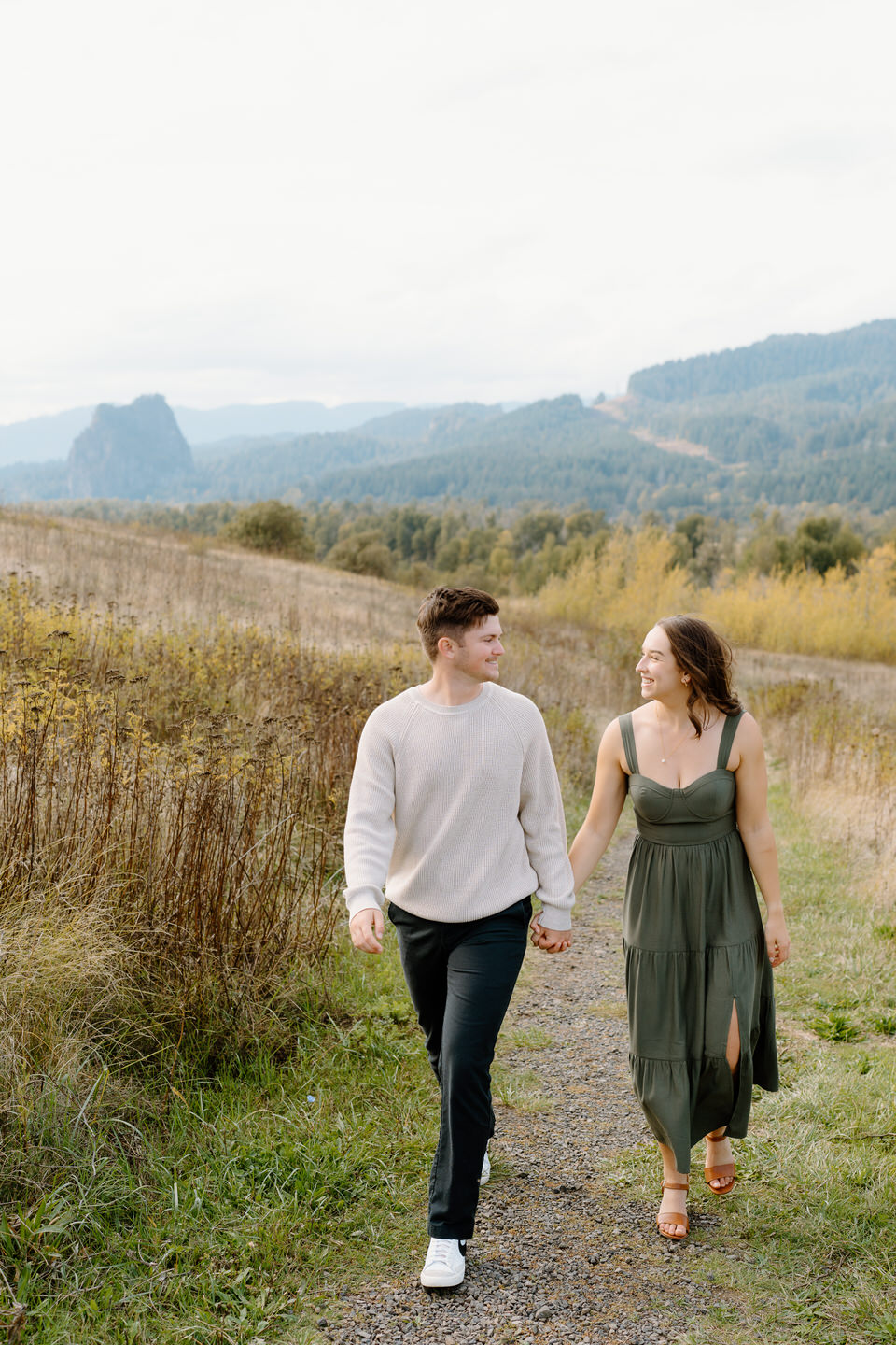 Natural light portrait of engaged couple holding hands in a field — fall engagement photo in the Columbia Gorge.