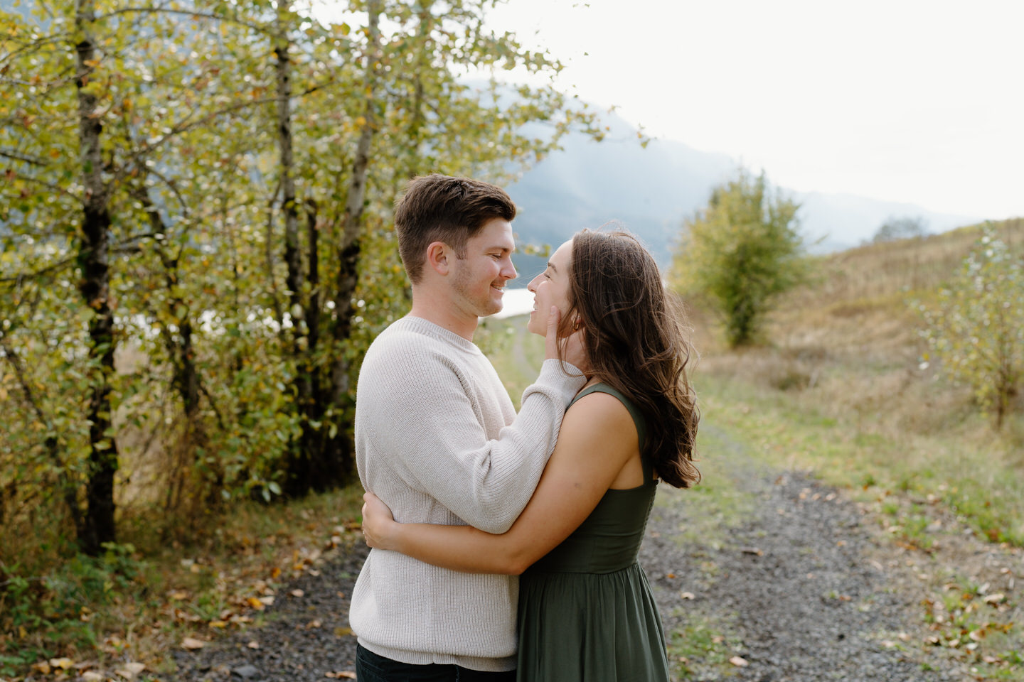 Man brushing woman’s hair away as she smiles — candid fall moment during Columbia Gorge engagement session.