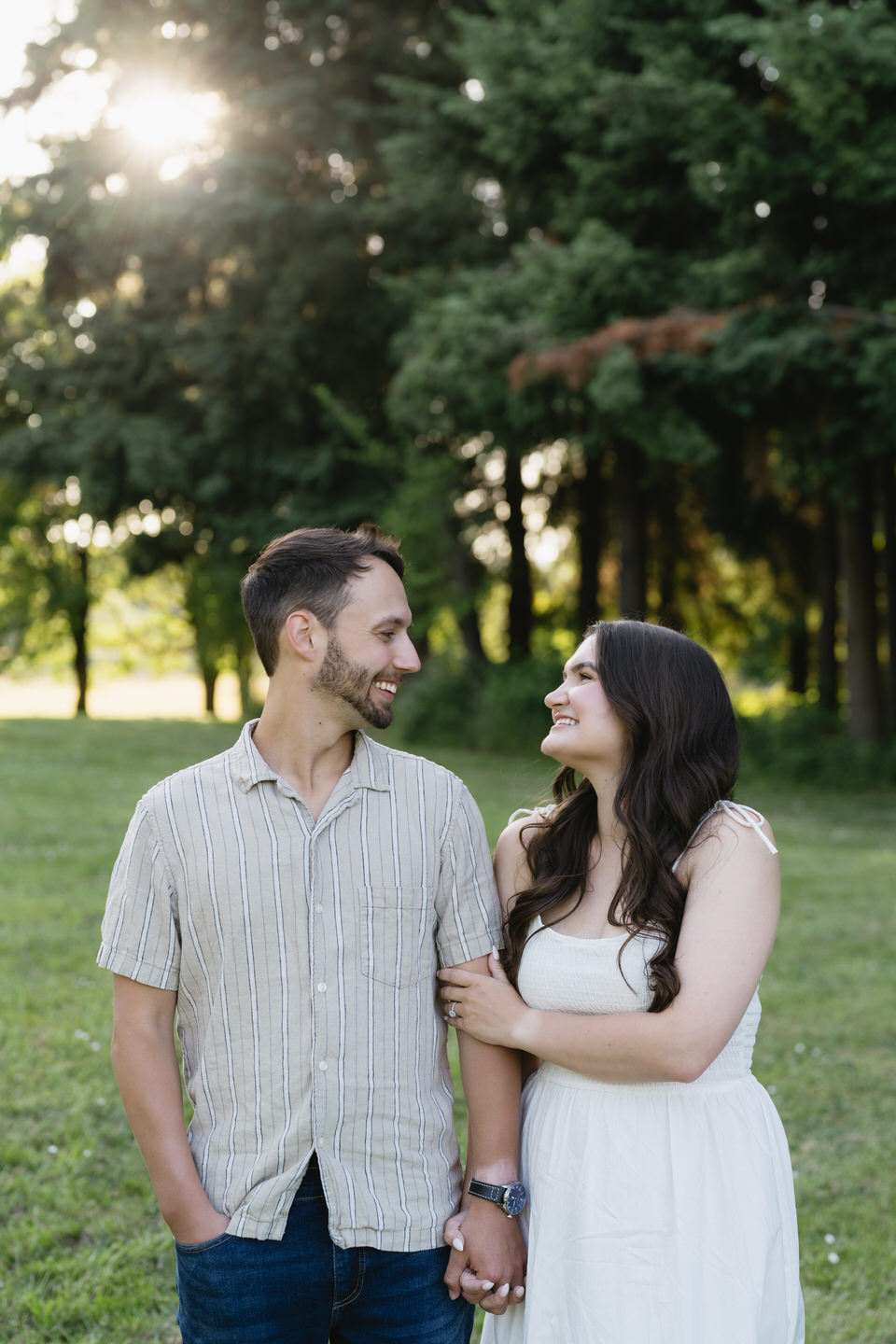 Woman wraps her arms around her fiancé's arm.