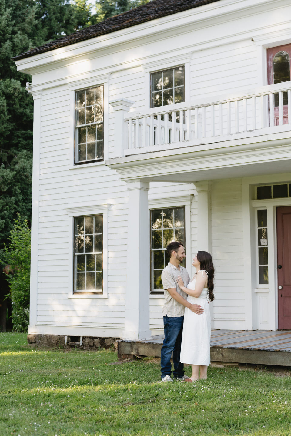 A white historical house with a balcony is a pretty engagement photo location in Portland.