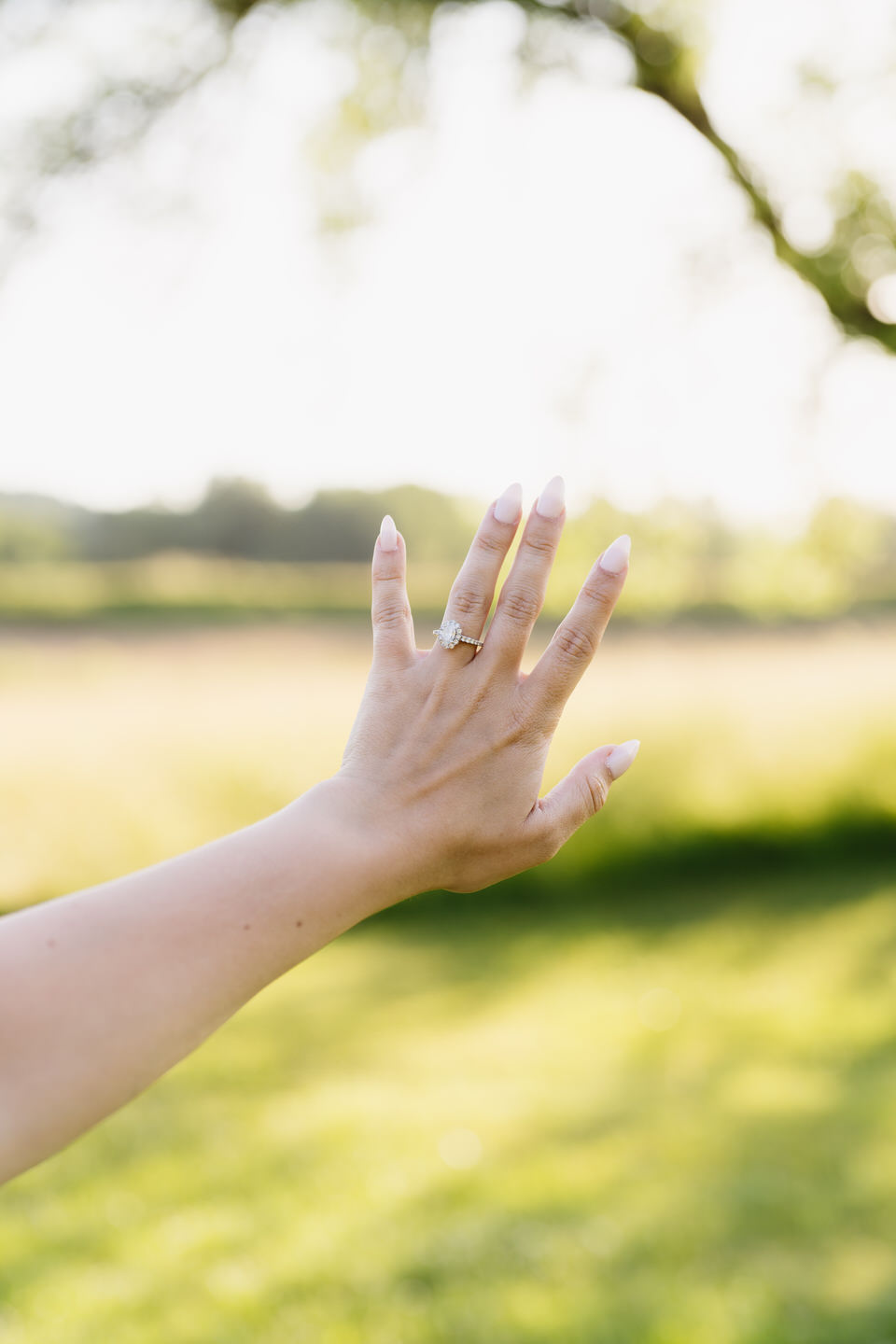 Woman holds her engagement ring up to the light.