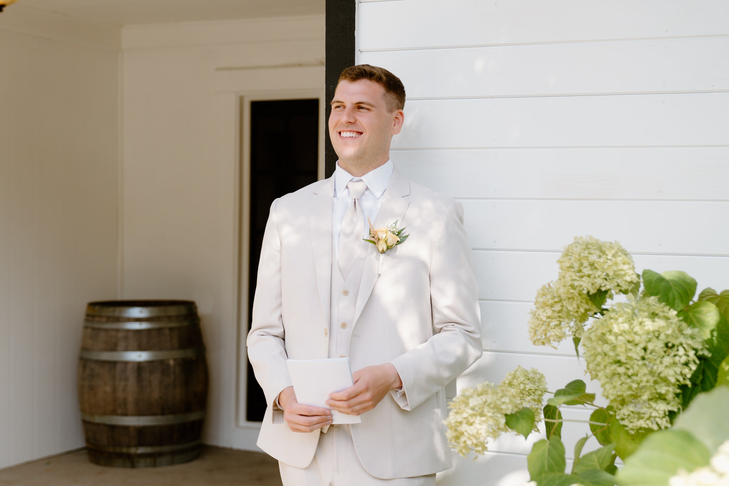 Groom holding his letter to the bride while wearing a light tan suit.