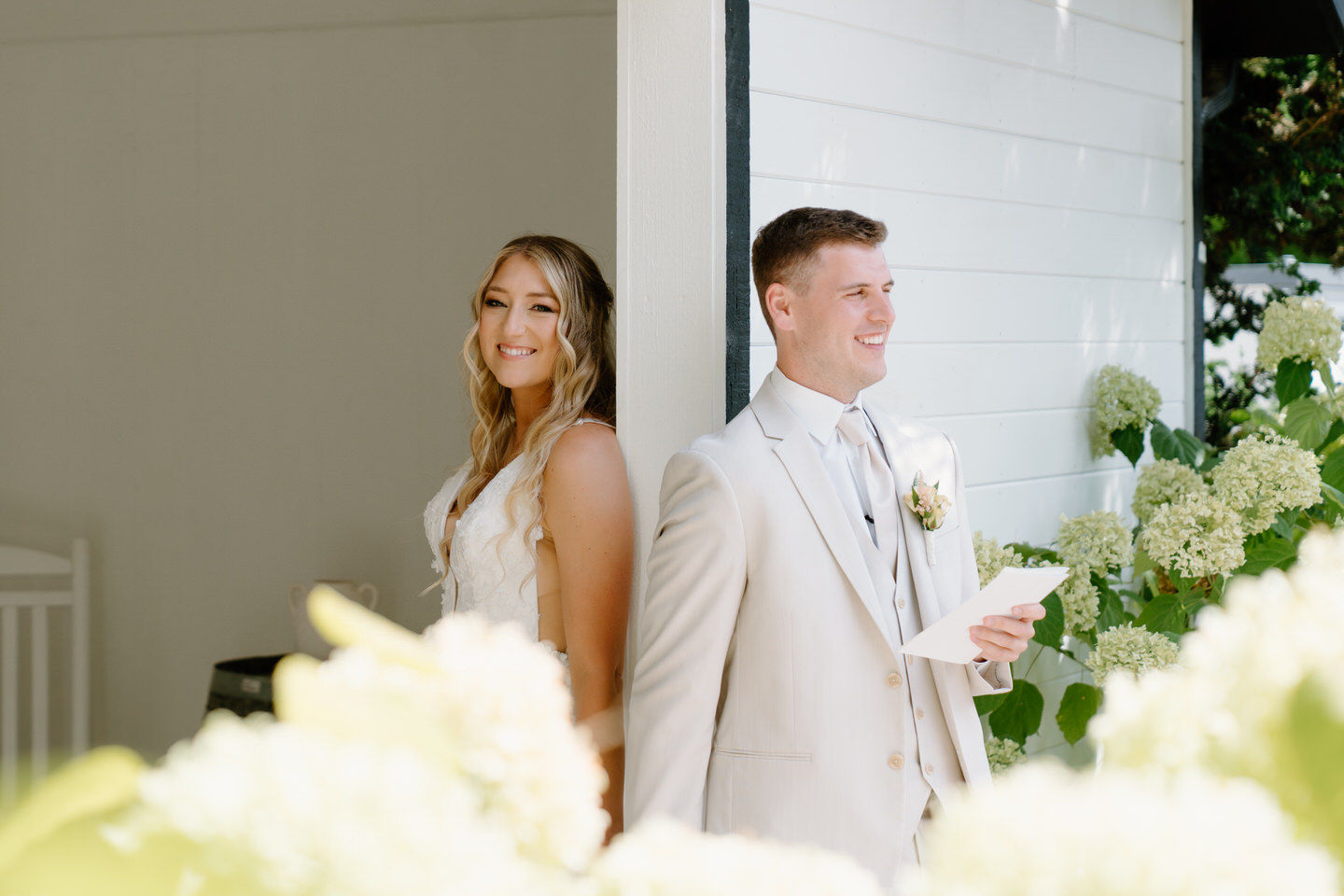 Bride and groom exchange letters in a private moment before the ceremony, surrounded by hydrangeas. 