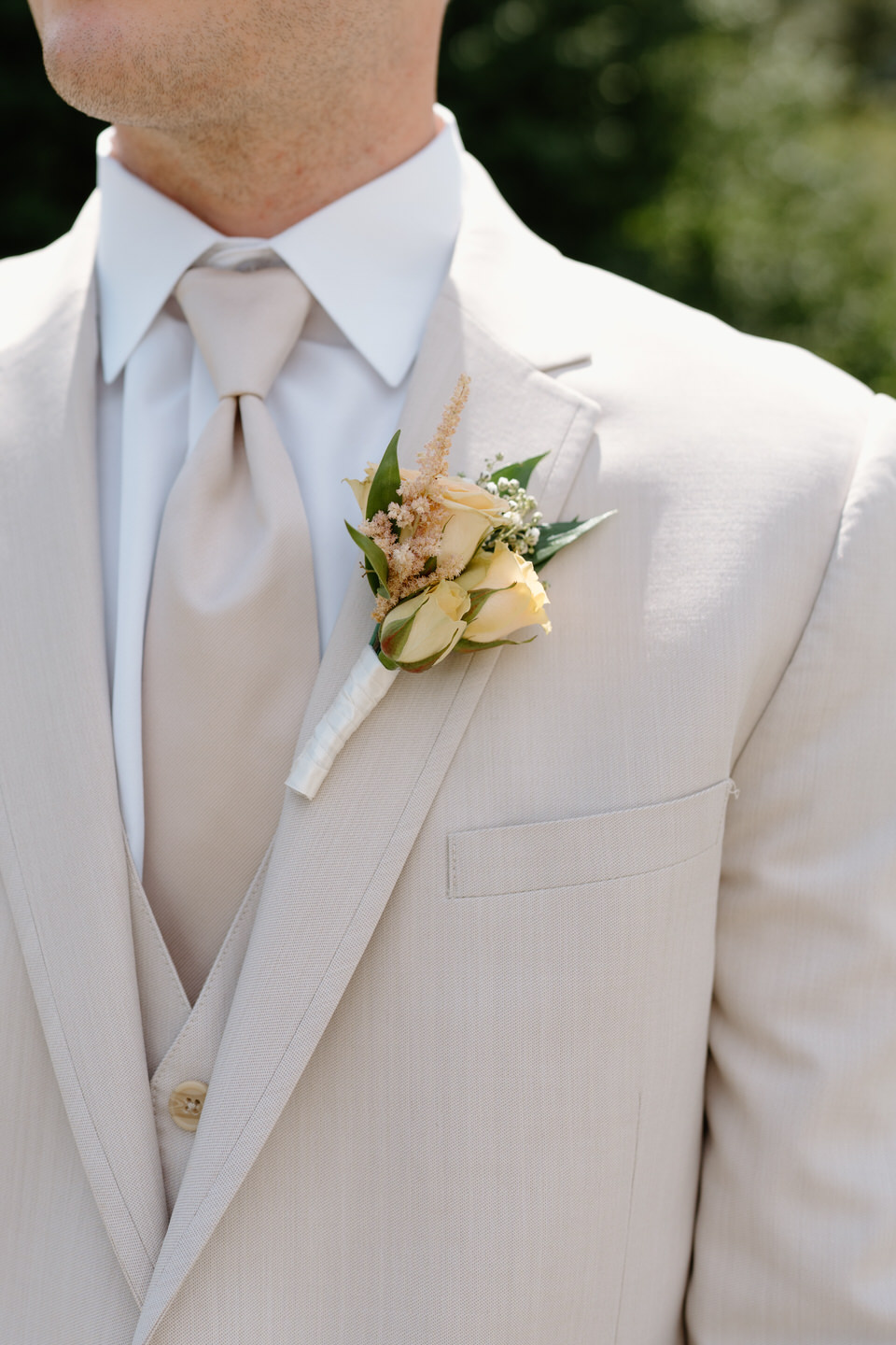 Groom's boutonniere pinned on his tan suit jacket.