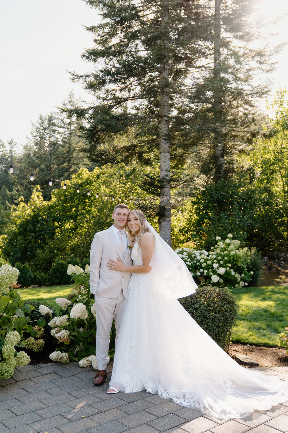 Couple smiling with hydrangeas and string lights in the background at Cape Horn Estate.