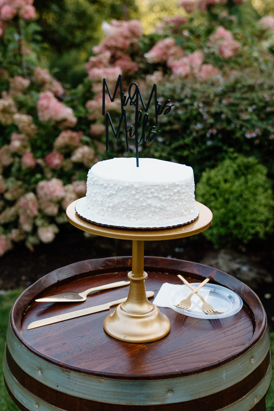 Single-tier wedding cake covered in pearls with a black "Mr. and Mrs." cake topper.