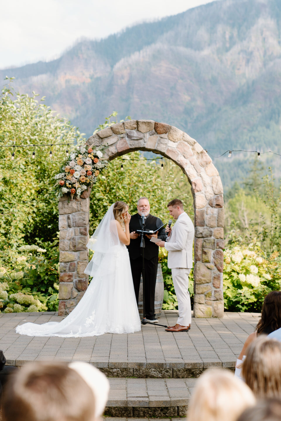 Bride wipes a tear away as the groom reads his vows with the Columbia River Gorge in the background. 