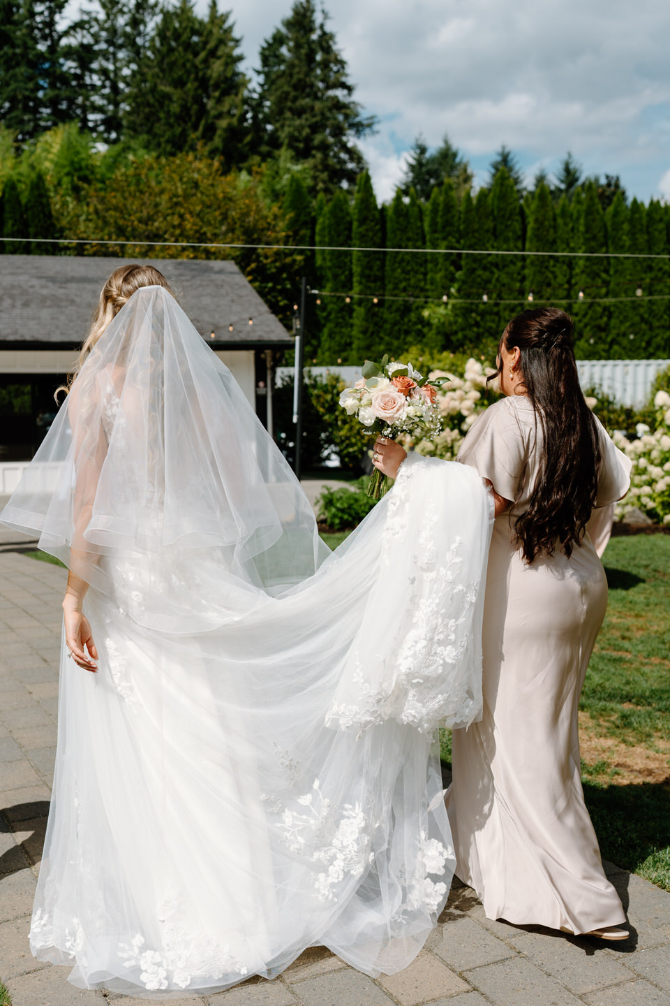 Maid of honor carrying the bride's train through the reception space at Cape Horn Estate.