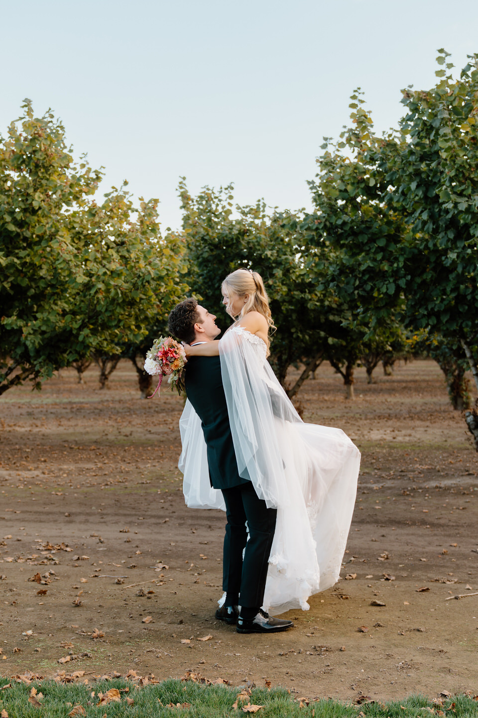 Groom lifting up the bride and twirling her around with her sleeves draped.