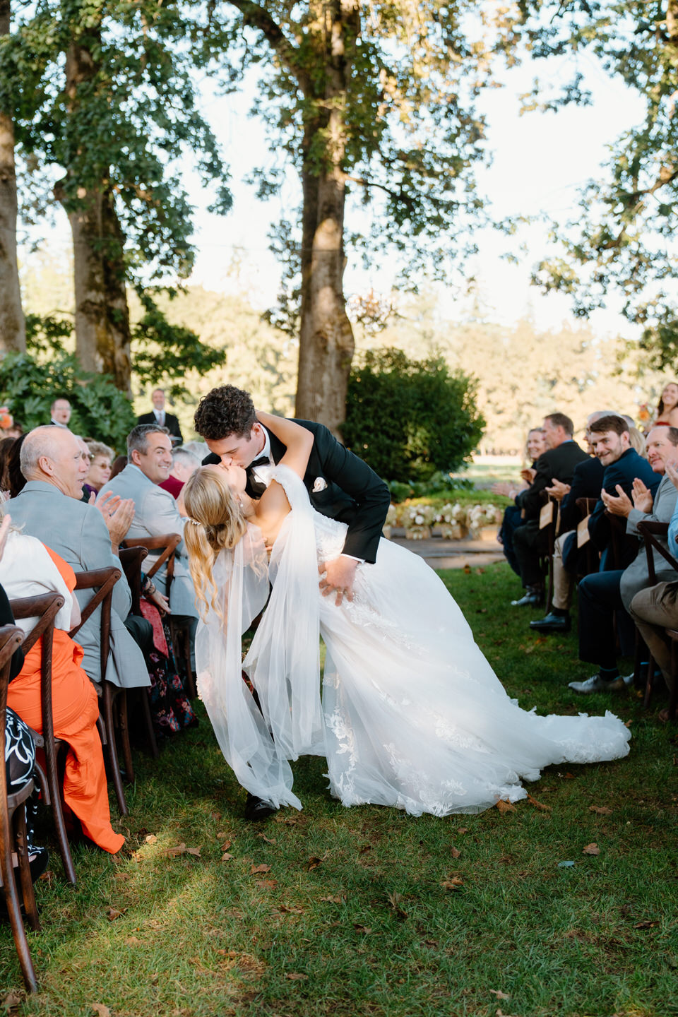 Dip kiss as the couple comes back down the aisle after their ceremony in the oak trees.
