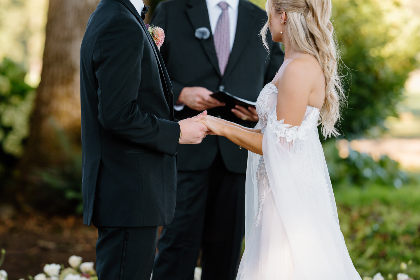 Close up of bride and groom holding hands as officiant reads the ceremony script.