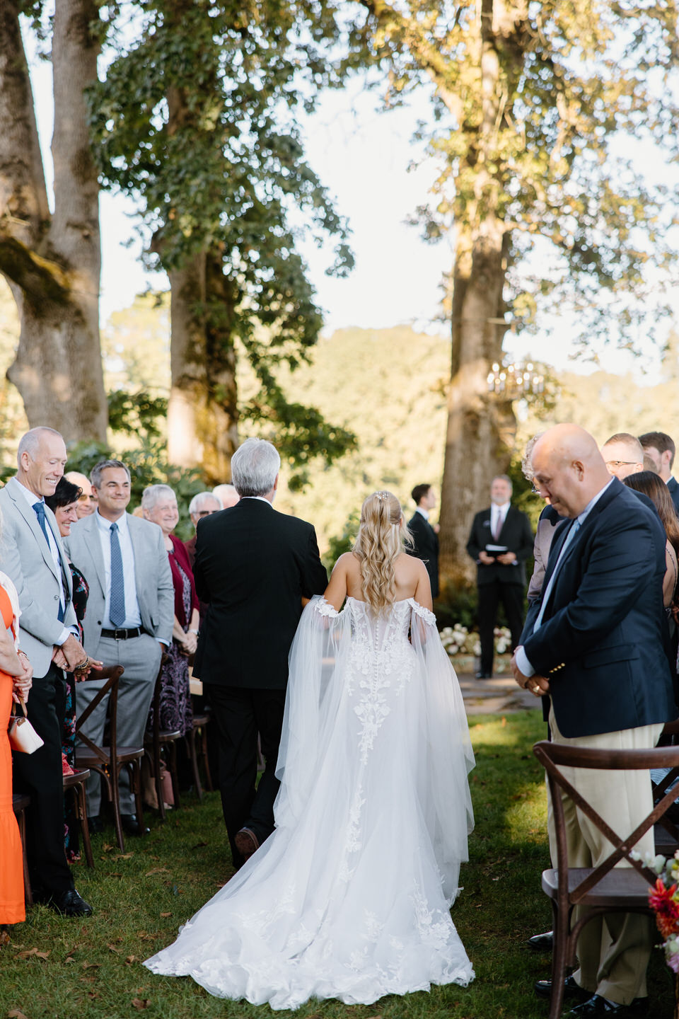 Rear-view of bride being walked down the aisle by her father.