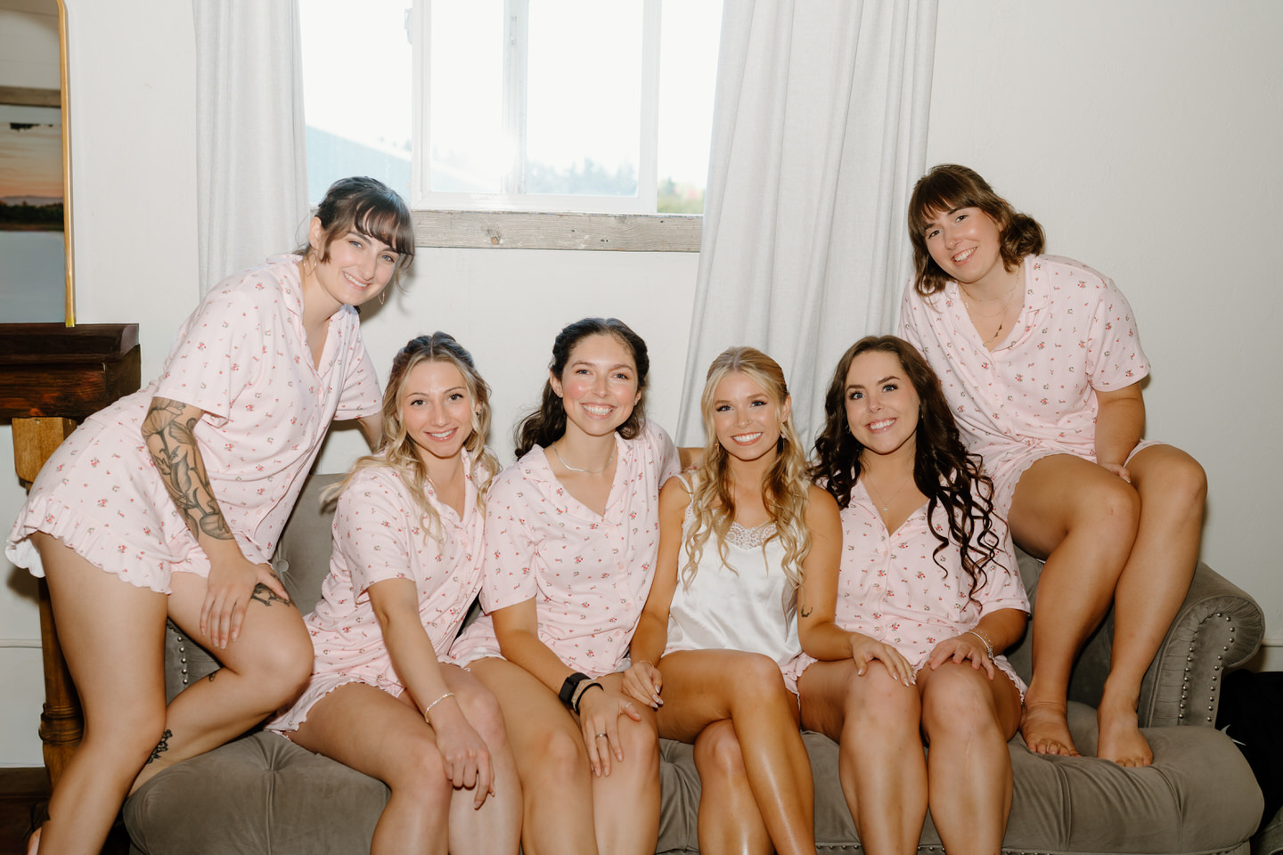 Bridesmaids smile together on the couch in the bridal suite at Postlewaits.