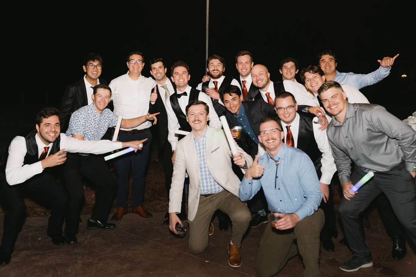 Groom and his friends smile for a photo on the dance floor.