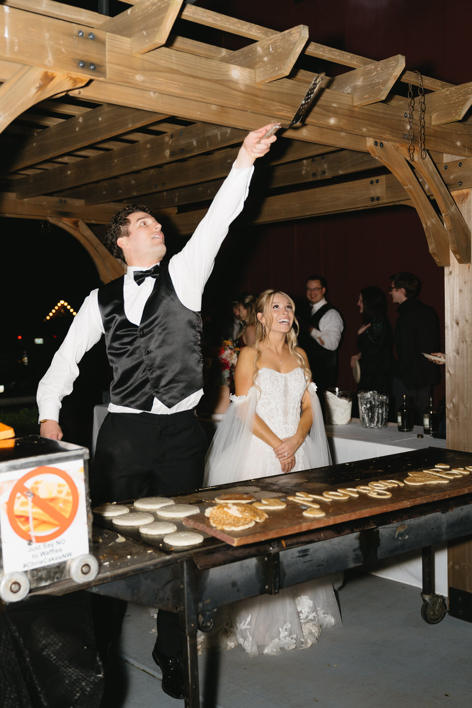 Groom flipping pancakes for wedding guests as a late night snack.