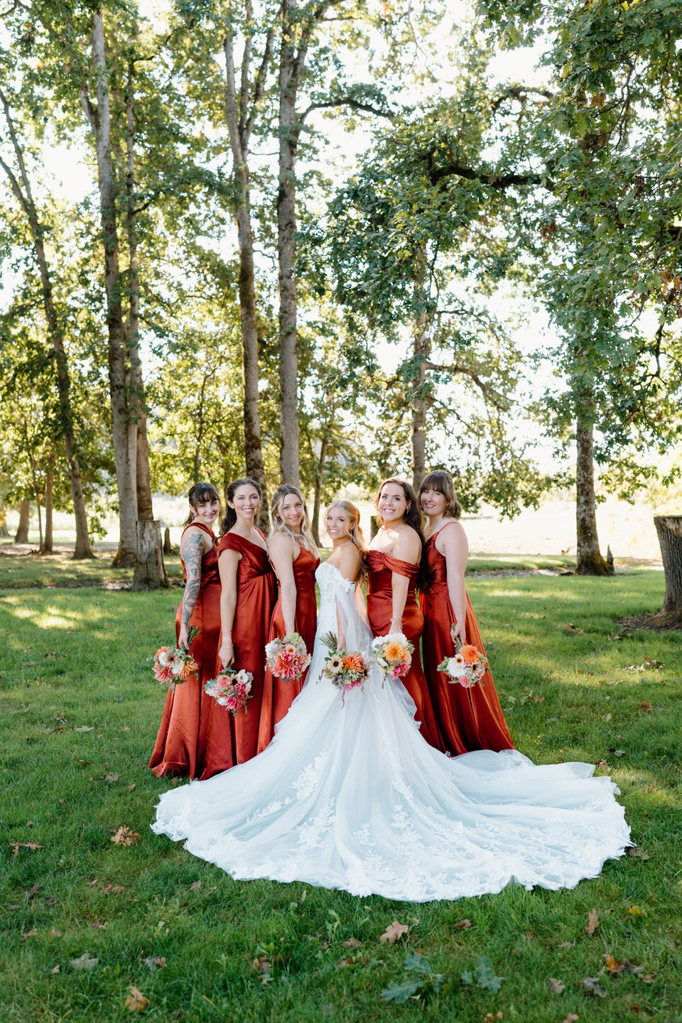 Bride and bridesmaids pose together, showing off the bride's train for her fall wedding.