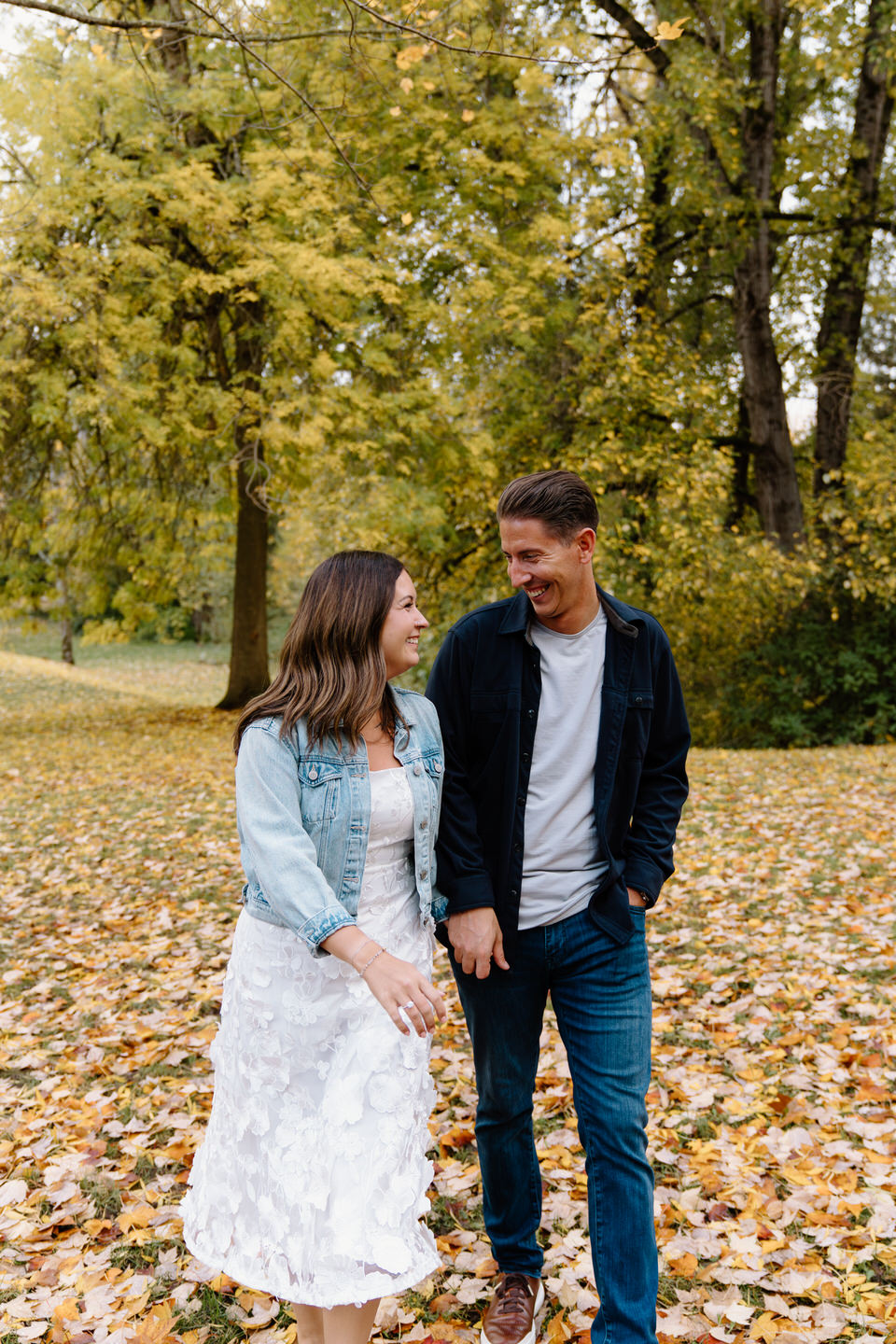 Couple skipping through the leaves during their Cathedral Park engagement photos.