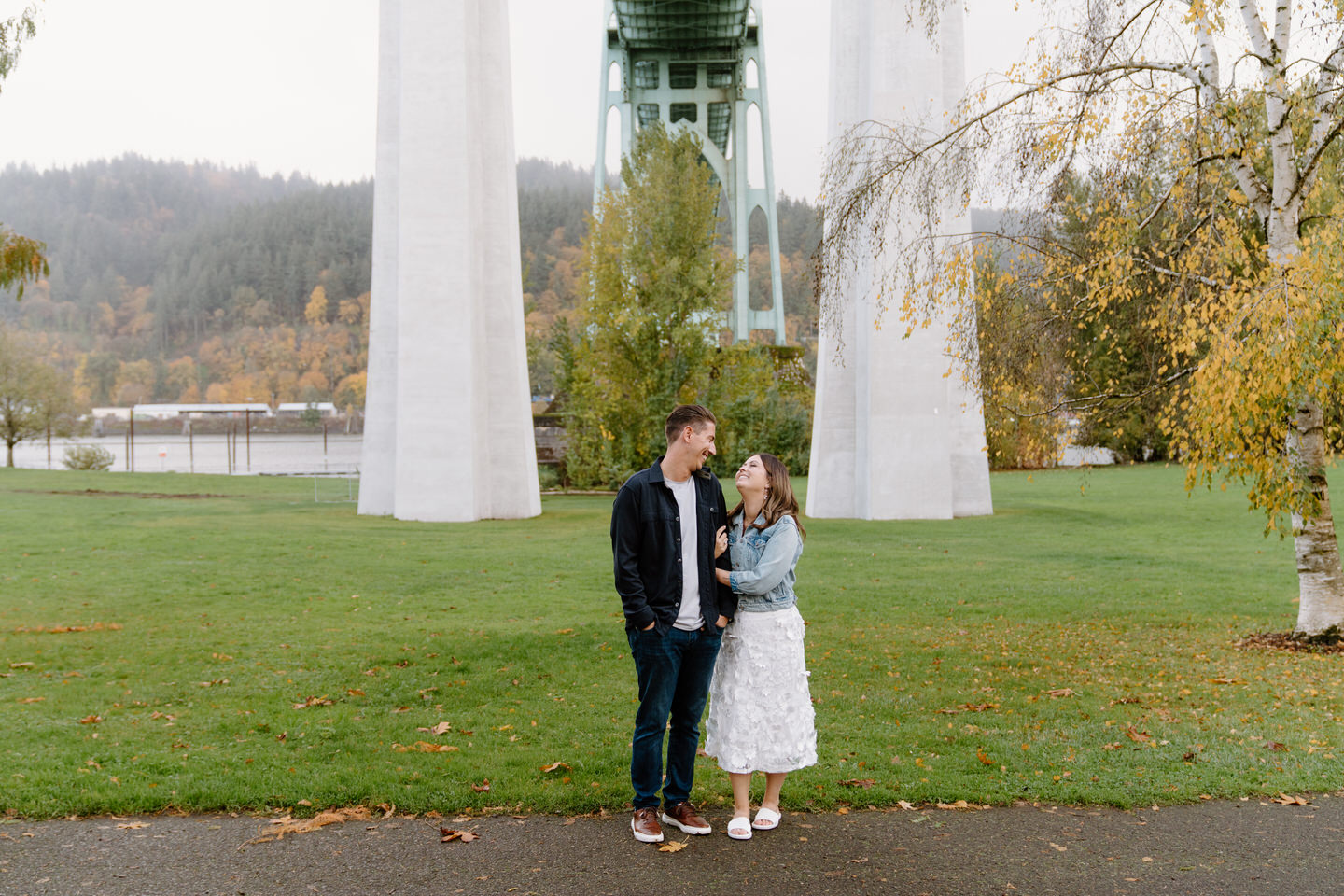 Couple looks at each other beneath the St. Johns Bridge at Cathedral Park engagement session.