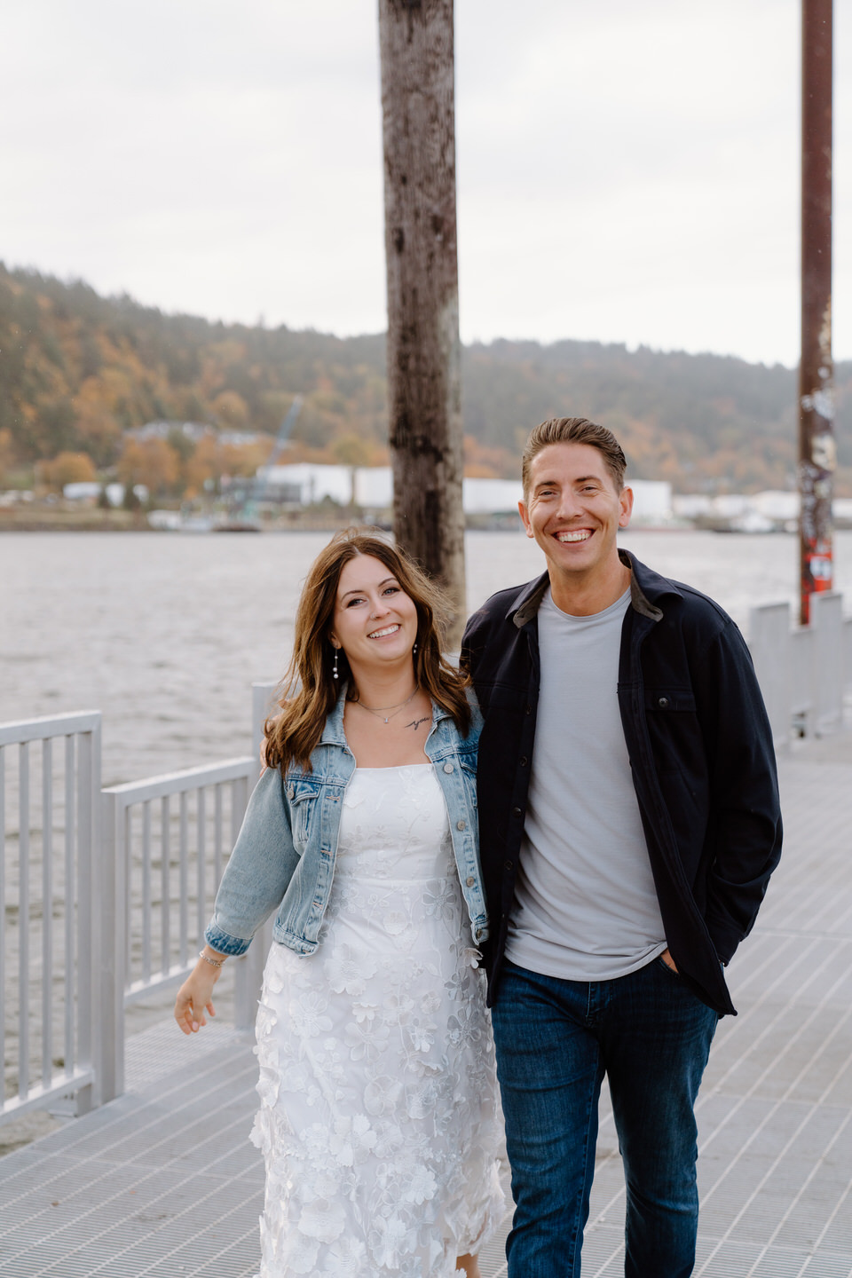 Couple with arms around each other walking on the dock beneath the St. Johns Bridge in Portland, Oregon.