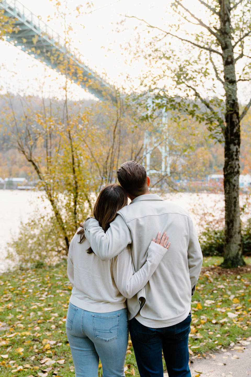 Couple stands with their back to the camera, looking out at the St. Johns Bridge in Portland, OR.