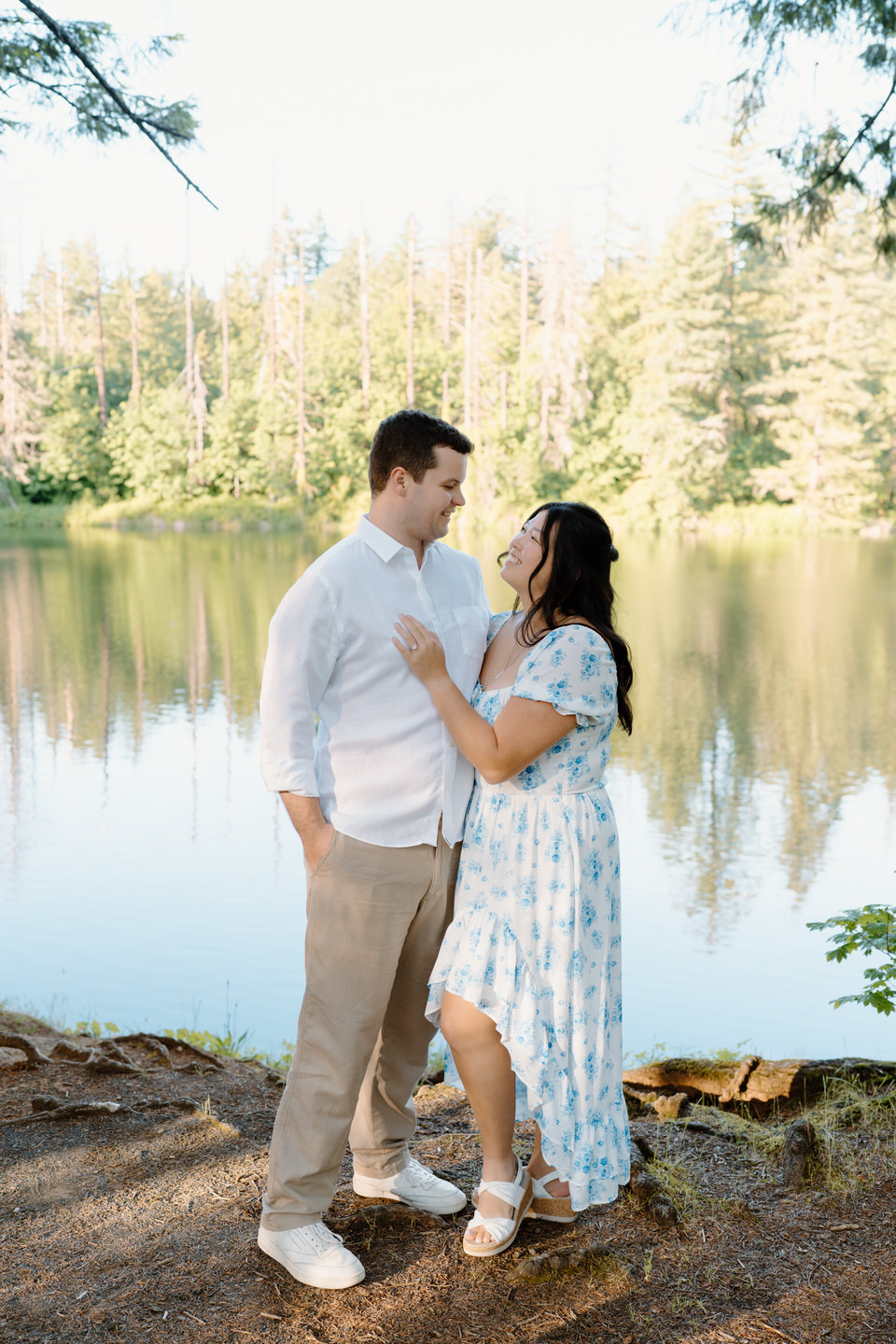 The couple embraces tightly on a scenic overlook, rolling hills and soft light creating a romantic outdoor moment.