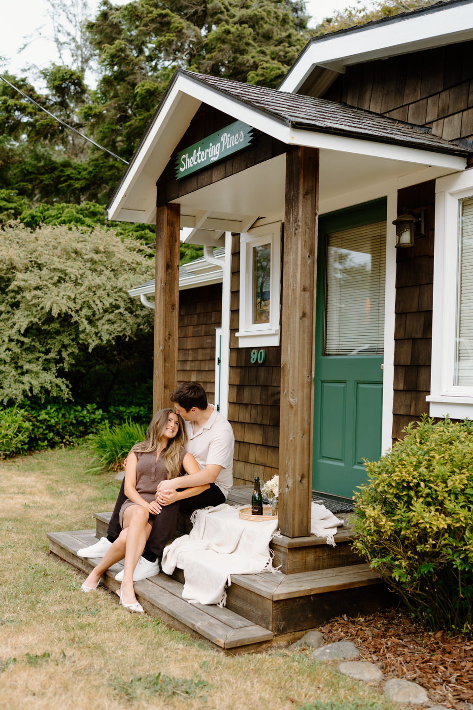 Couple cuddles on the front porch for their Manzanita engagement photos.