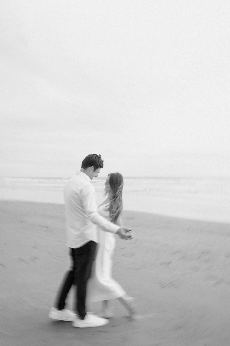 Black and white photo of a couple dancing on the beach.