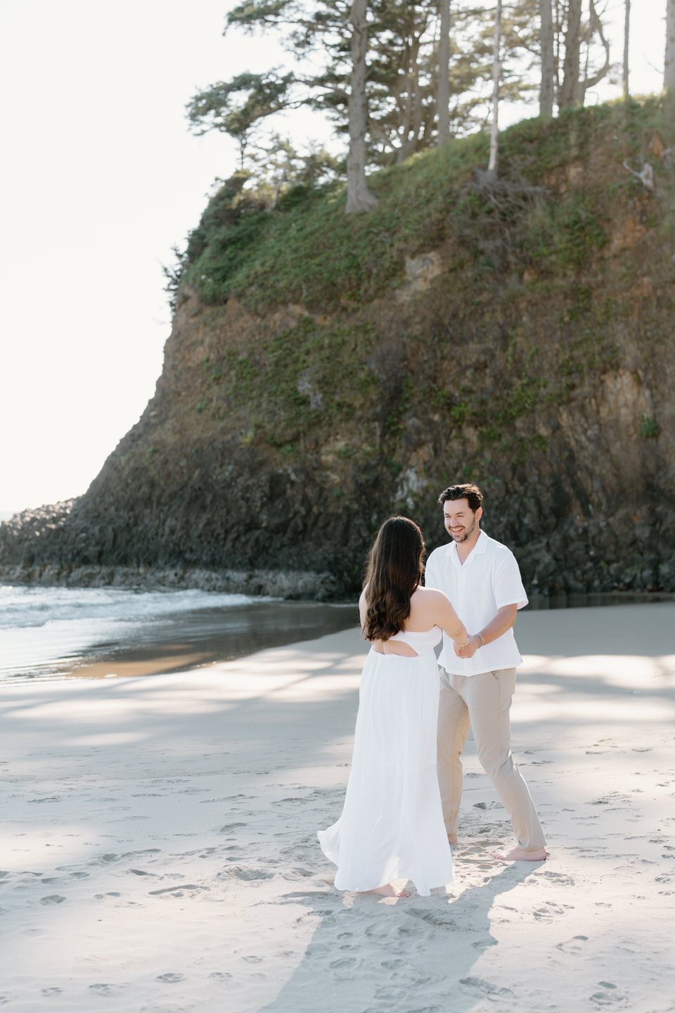 Playful engagement photos with the couple holding hands and spinning around on the sand.