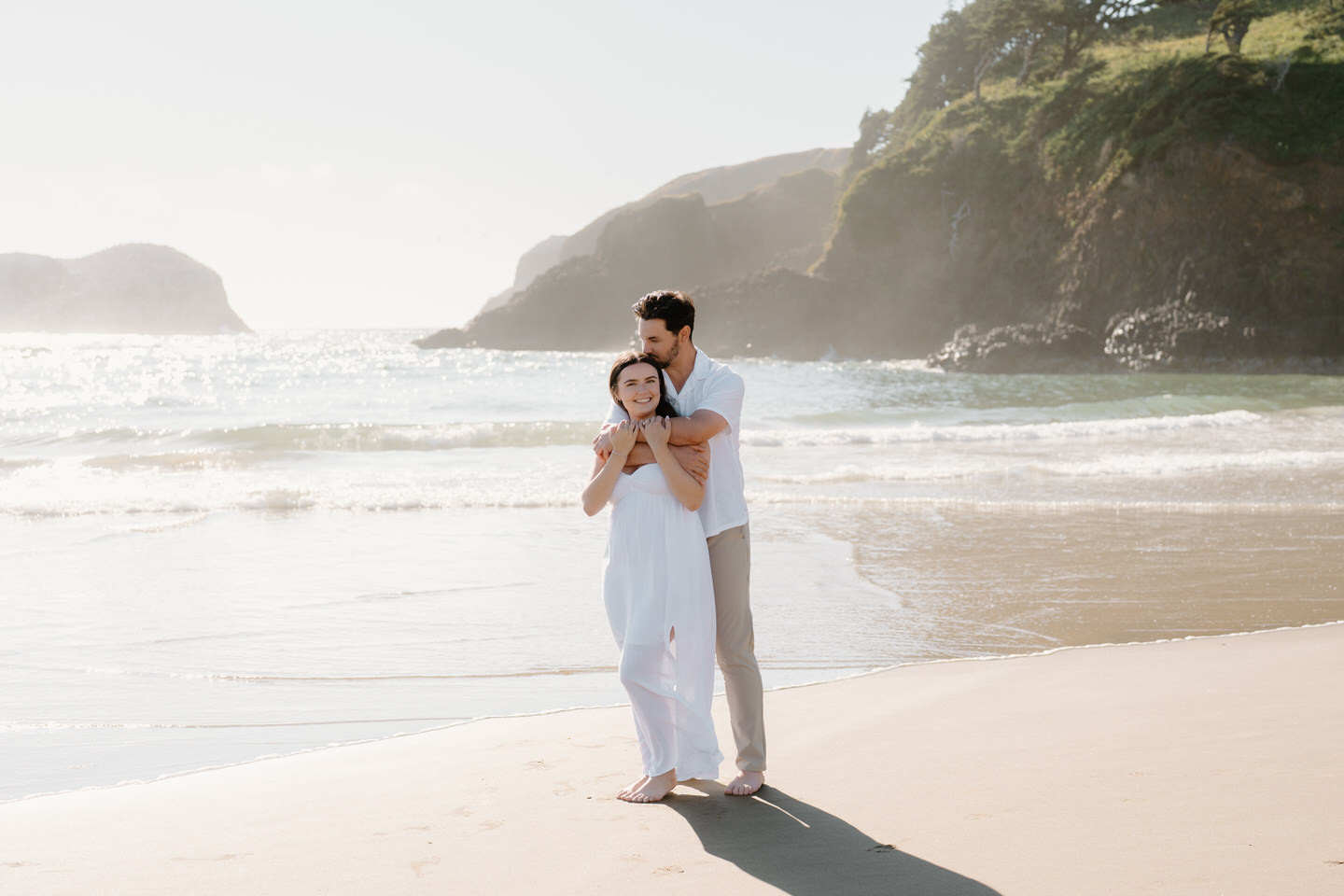 Dreamy Oregon coast engagement photos with sun shining through the ocean mist.